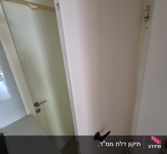 דלת פתוחה עם ידית שחורה וצירים גלויים